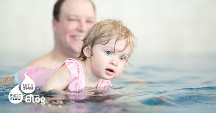 Bébé dans l’eau avec son papa pendant un cours de bébés nageurs First Flow